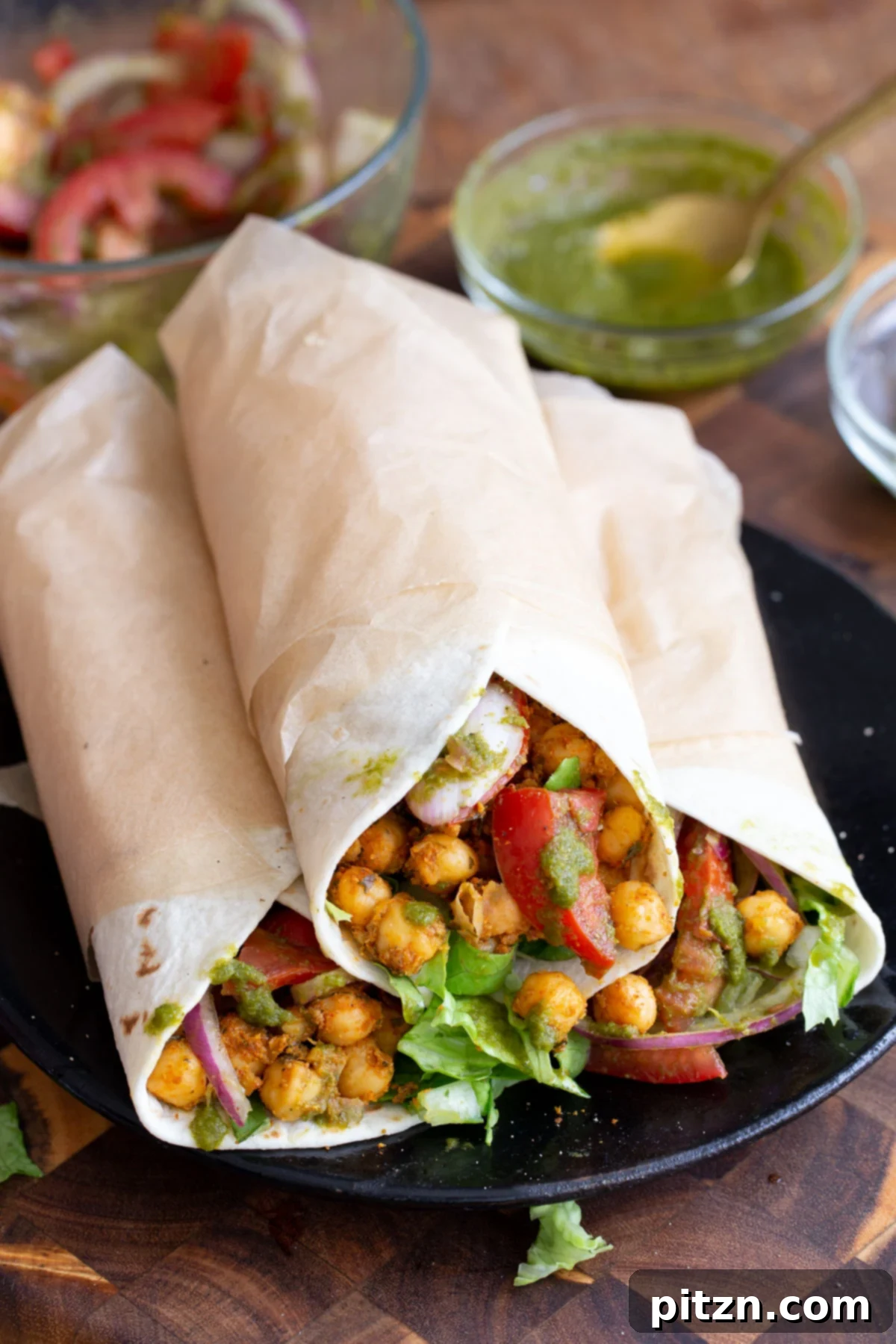 Tangy Chickpea Wraps 4 Three open Indian spiced chickpea wraps, brimming with seasoned chickpeas, fresh tomato slices, and crisp lettuce, ready to be rolled.