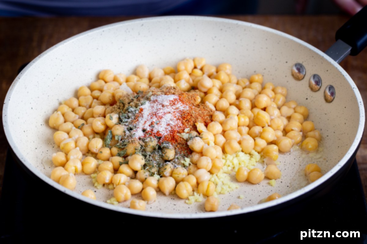 Tangy Chickpea Wraps 6 Drained chickpeas being added to a skillet with a vibrant array of Indian spices, ready to be cooked.