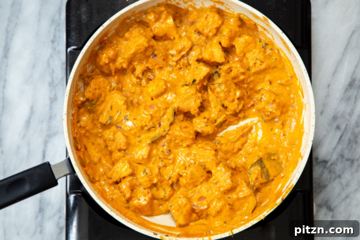 Flavorful Lasooni Vegan Chicken Curry, Entirely Tomato-Free 15 Overhead shot of a large pan filled with creamy vegan Lasooni Tofu curry, garnished with fresh herbs.