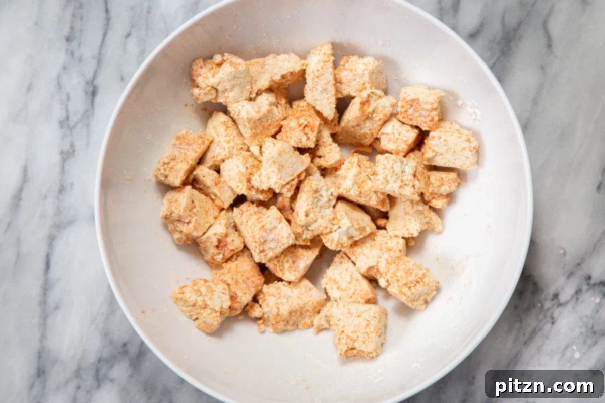 Flavorful Lasooni Vegan Chicken Curry, Entirely Tomato-Free 8 Seasoned tofu chunks, beautifully coated with spices and cornstarch, spread on a baking sheet, ready for the oven.
