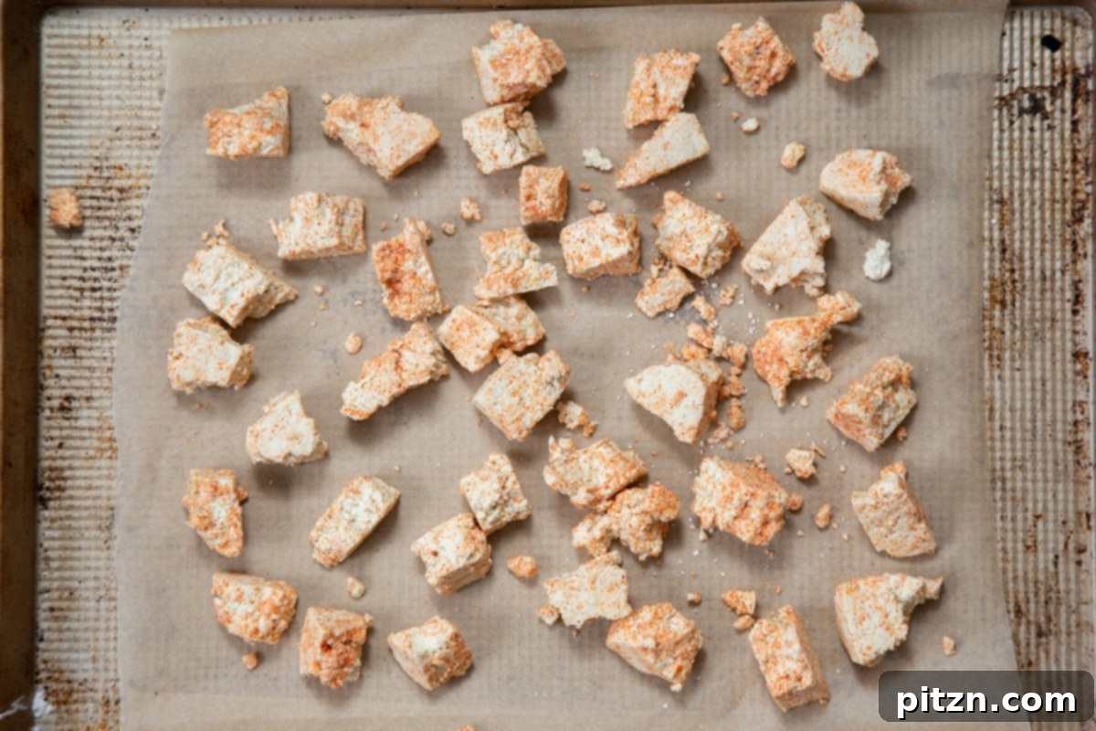 Flavorful Lasooni Vegan Chicken Curry, Entirely Tomato-Free 9 Torn, seasoned tofu chunks baking on a parchment-lined sheet, crisping up for the Lasooni curry.
