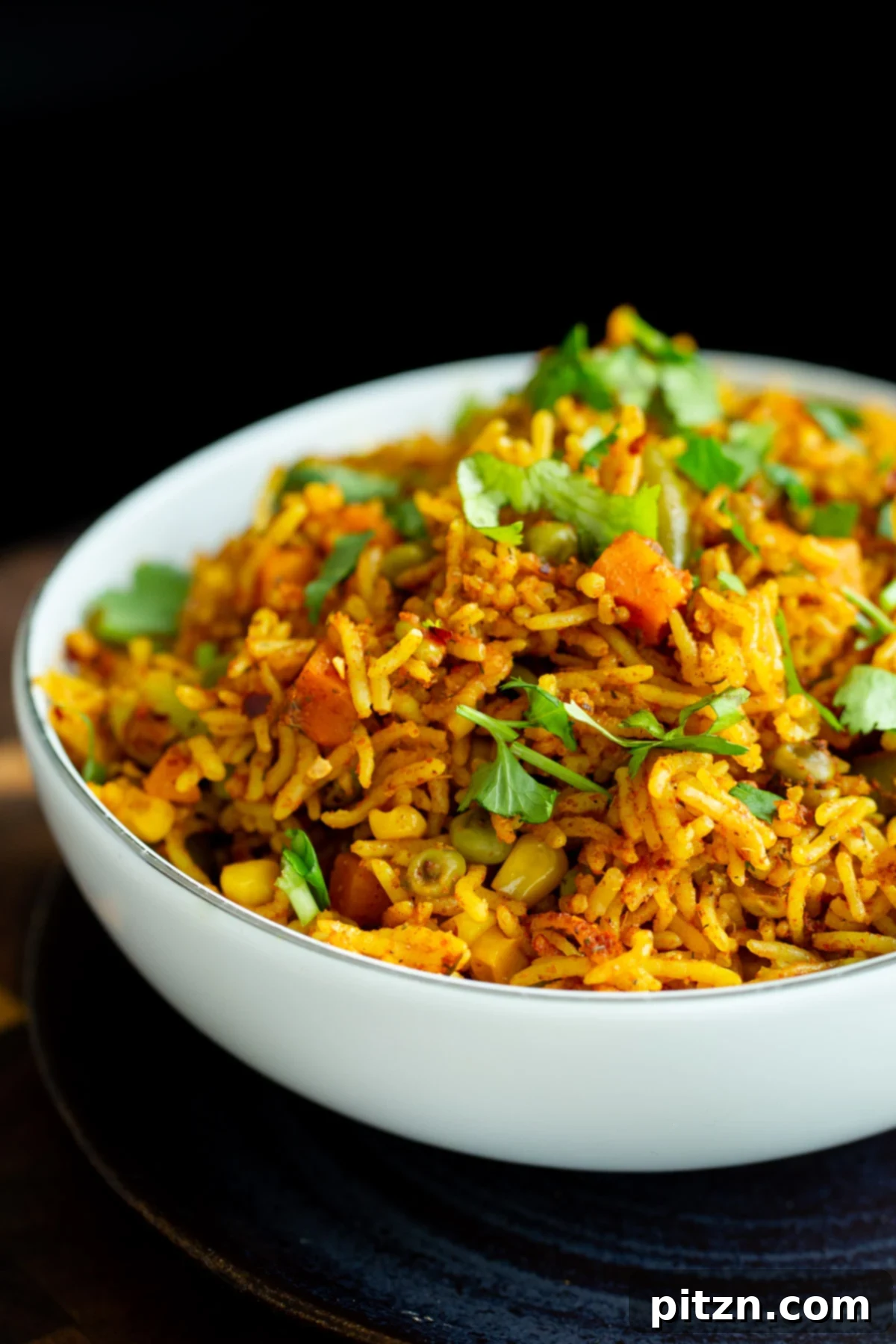 A white bowl showcasing a vibrant vegan baked masala rice casserole, garnished with fresh cilantro.