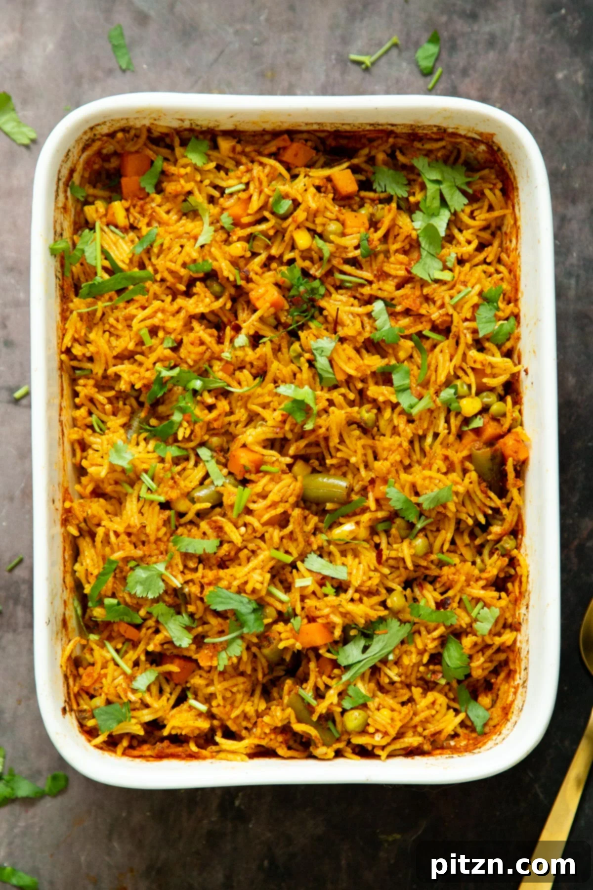 A close-up view of a casserole dish filled with baked masala rice, highlighting its fluffy texture and vibrant colors.