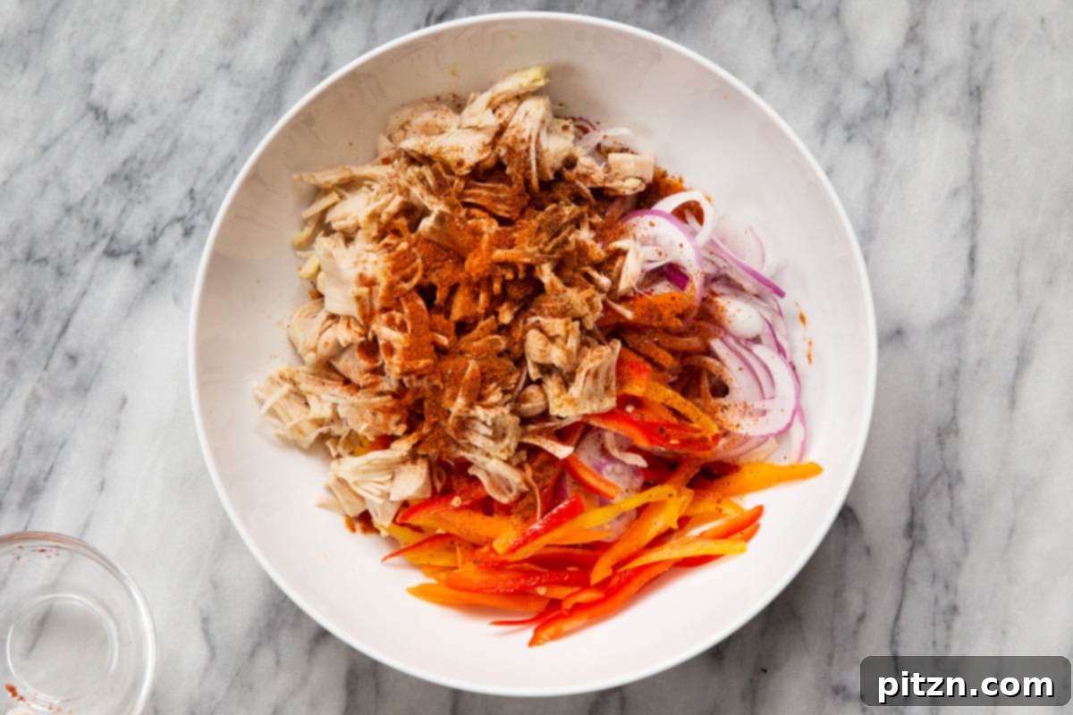 Quick & Easy Vegan Jackfruit Tacos 12 shredded jackfruit in a white bowl with spices, bell pepper and onions
