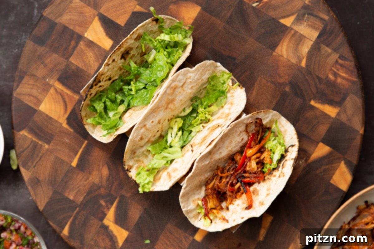 Quick & Easy Vegan Jackfruit Tacos 17 three tacos being assembled with lettuce and jackfruit
