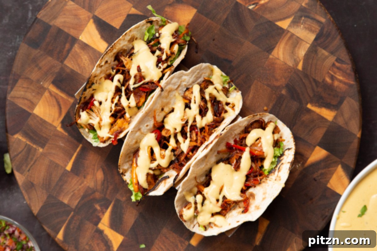 Quick & Easy Vegan Jackfruit Tacos 19 three fully assembled vegan jackfruit tacos on a wooden board