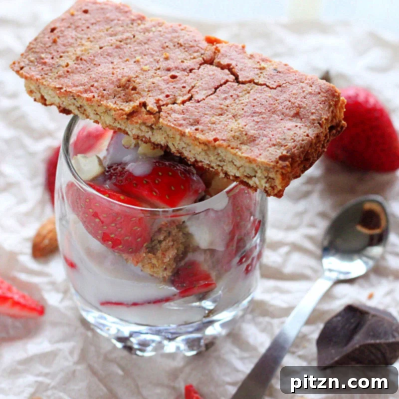 Vegan Gluten-Free Gum-Free Spiced Oat Almond Cake Parfait with Strawberry, Nuts & Goji Berries 3 Close-up of a glass parfait with layered spiced oat almond gluten-free cake, fruit, and vegan yogurt, with a focus on the vibrant layers