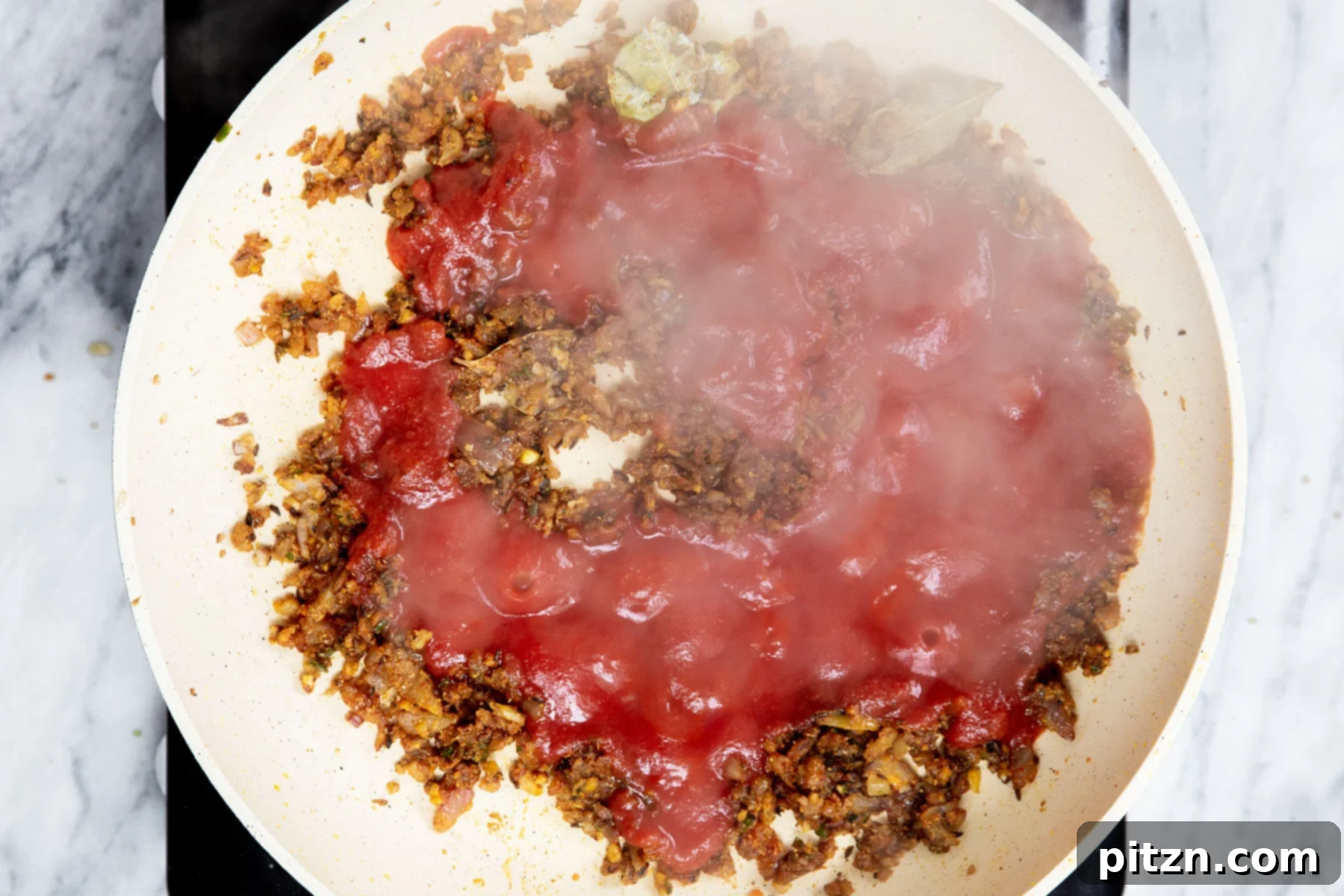 Vegan Tofu Matar 19 tomato paste being added to a sauteein pan with onion and spices