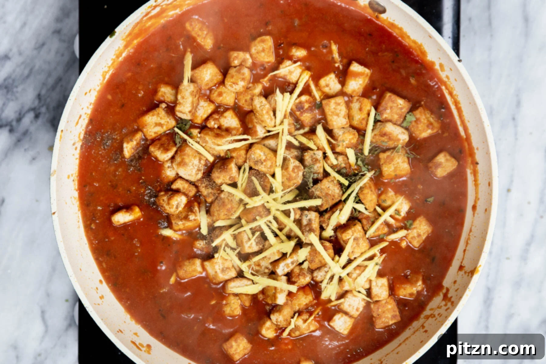 Vegan Tofu Matar 21 baked tofu being added to a sauteeing pan with spiced tomato sauce