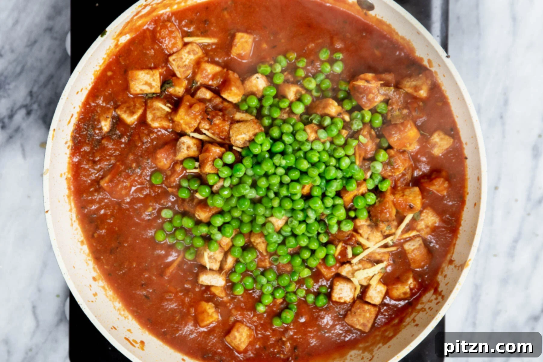Vegan Tofu Matar 22 peas being added to Indian tofu curry in a sauteeing pan