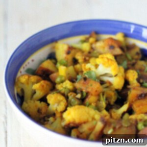 Vegan Aloo Gobi in a blue-rimmed bowl on a white marble worktop, garnished with fresh cilantro.