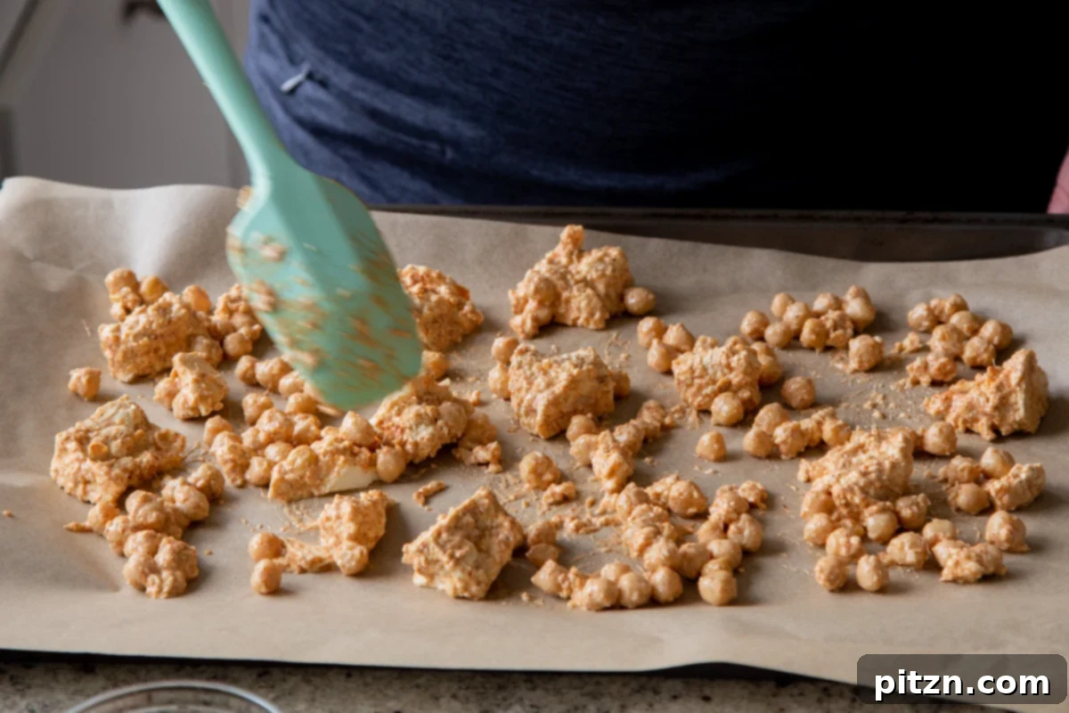 Creamy Fenugreek Tofu and Chickpea Curry 10 Seasoned chickpeas and tofu spread on a parchment-lined baking sheet before baking
