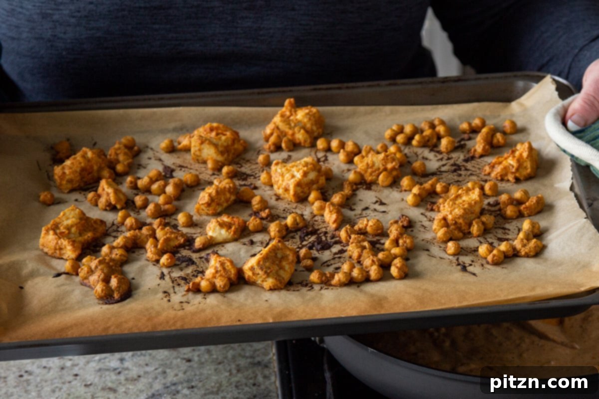 Creamy Fenugreek Tofu and Chickpea Curry 11 Baked seasoned chickpeas and tofu on the baking sheet after cooking, golden and crispy