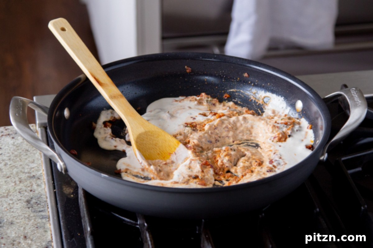 Creamy Fenugreek Tofu and Chickpea Curry 16 Adding vegan cashew cream to the pan of spices and onions before mixing