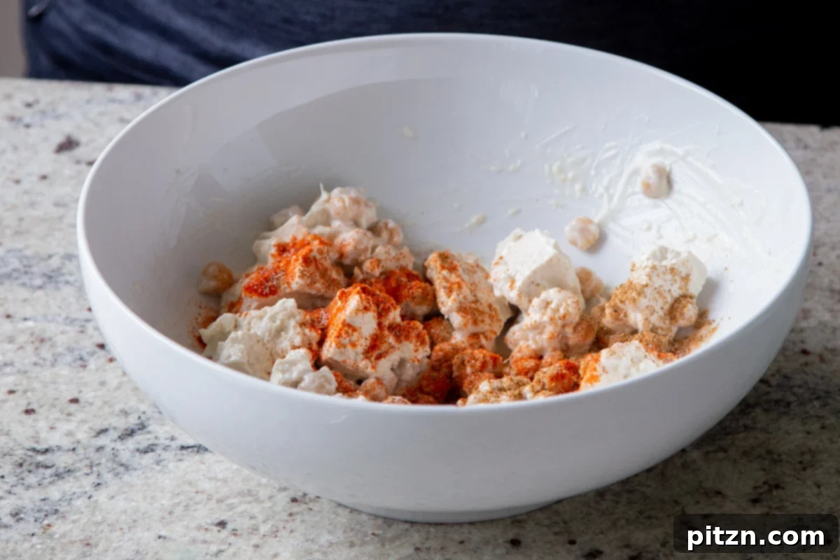 Creamy Fenugreek Tofu and Chickpea Curry 8 Torn tofu and chickpeas in a bowl with non-dairy cream and spices added, before mixing