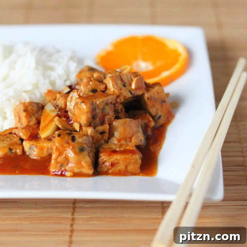 General Tso's Tempeh served with rice and broccoli, garnished with green onions and orange slices