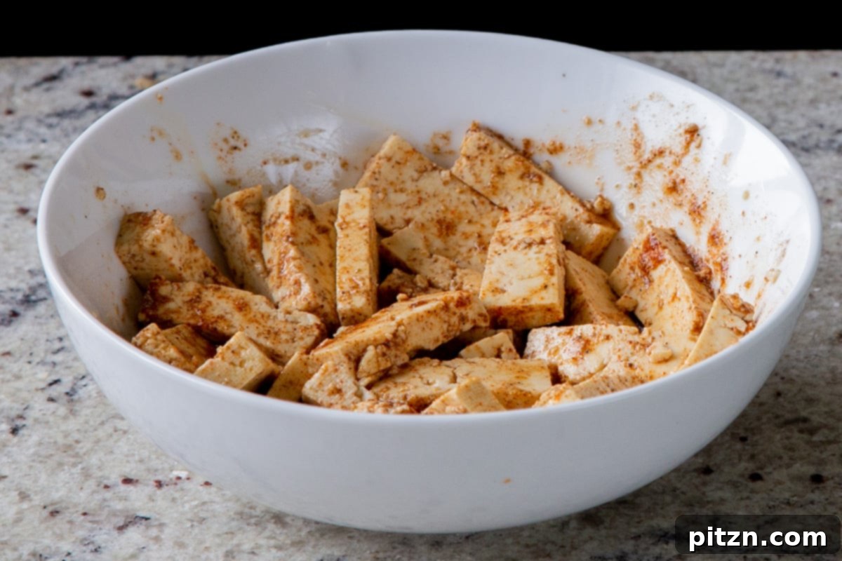 Decadent Vegan Butter Chicken Ramen 10 Tofu pieces evenly coated with a vibrant spice blend, ready for cooking.