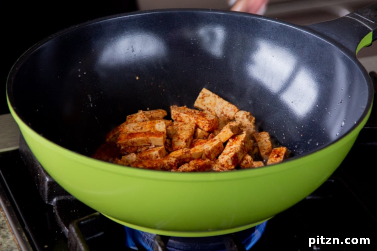 Decadent Vegan Butter Chicken Ramen 11 Crispy golden-brown tofu pieces being removed from a wok after cooking.