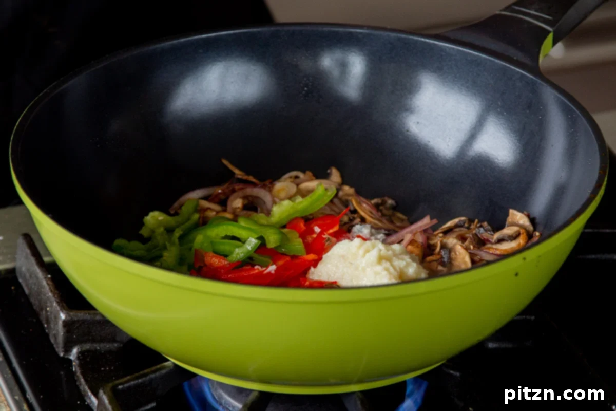 Decadent Vegan Butter Chicken Ramen 14 Adding thinly sliced bell peppers and ginger-garlic paste to the sautéed mushrooms and onions in the wok.