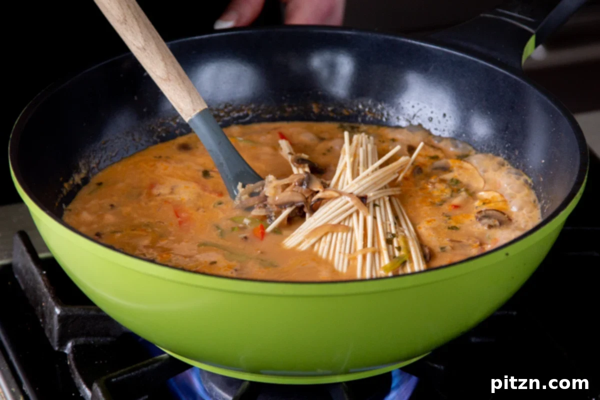 Decadent Vegan Butter Chicken Ramen 18 Ramen noodles added to the creamy coconut milk and vegetable mixture in the wok, ready to simmer.