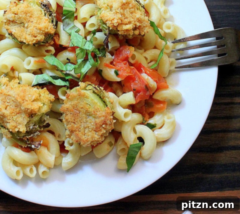 A close-up of pasta with a rich tomato basil sauce, topped with crispy breaded Brussels sprouts and fresh basil leaves
