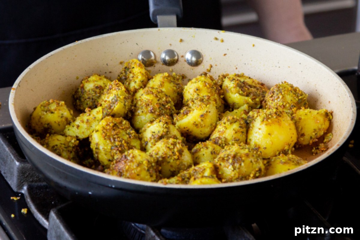 Peanut sesame potatoes freshly tossed and roasting in the frying pan, achieving a perfect golden crisp.