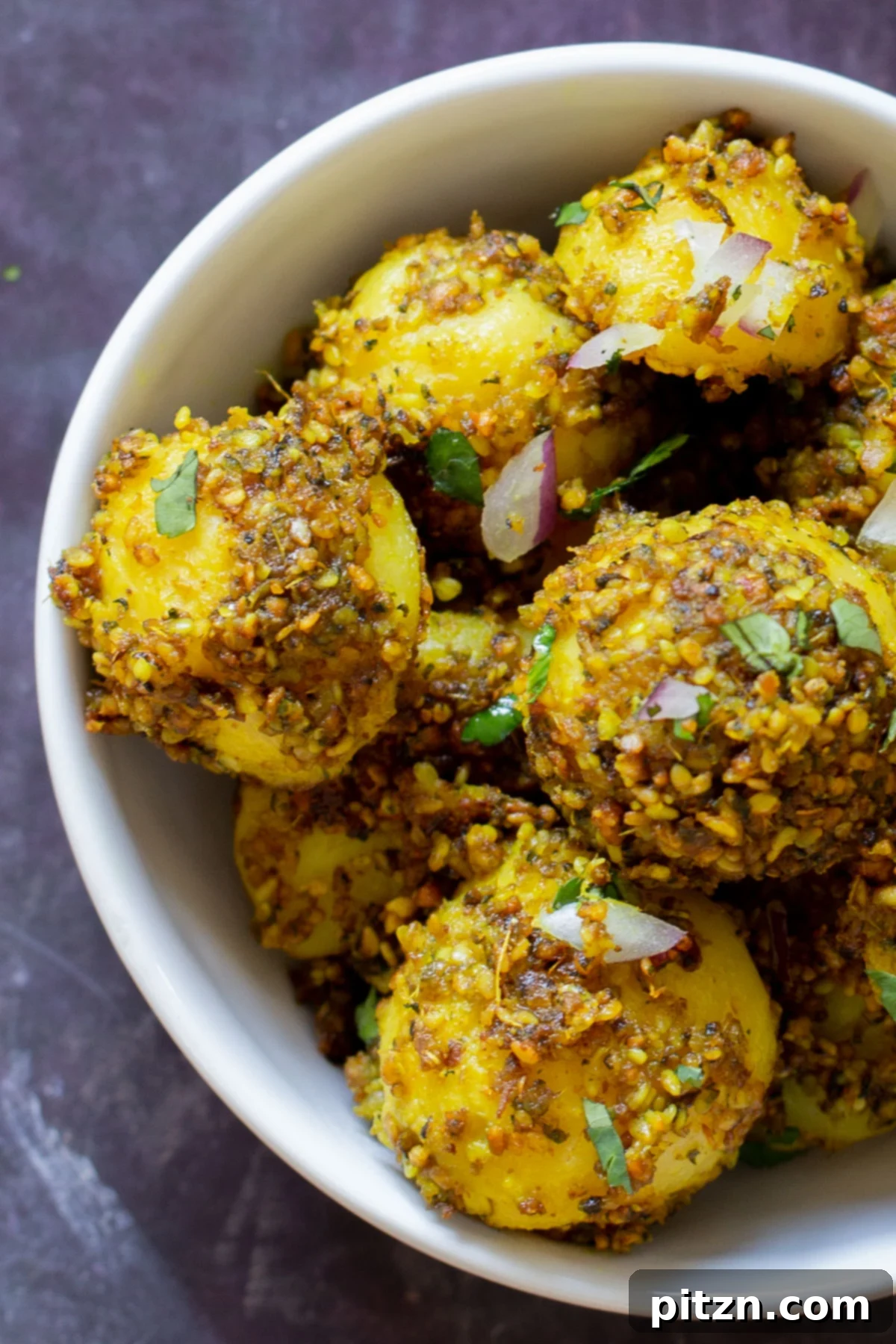 A close-up view of crispy peanut sesame potatoes in a bowl, showcasing the detailed spice and seed coating.