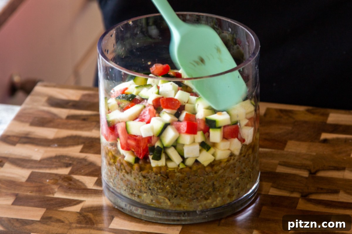 Effortless Lentil Quinoa Medley 15 A layer of chopped zucchini and tomatoes being added to the jar, providing moisture and vibrant color.