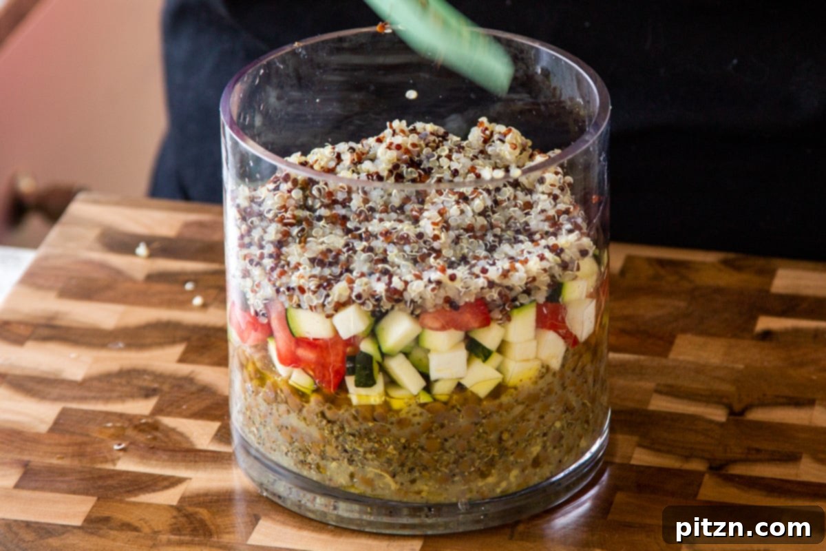Effortless Lentil Quinoa Medley 16 The fluffy cooked quinoa being added as another distinct layer in the glass jar salad.