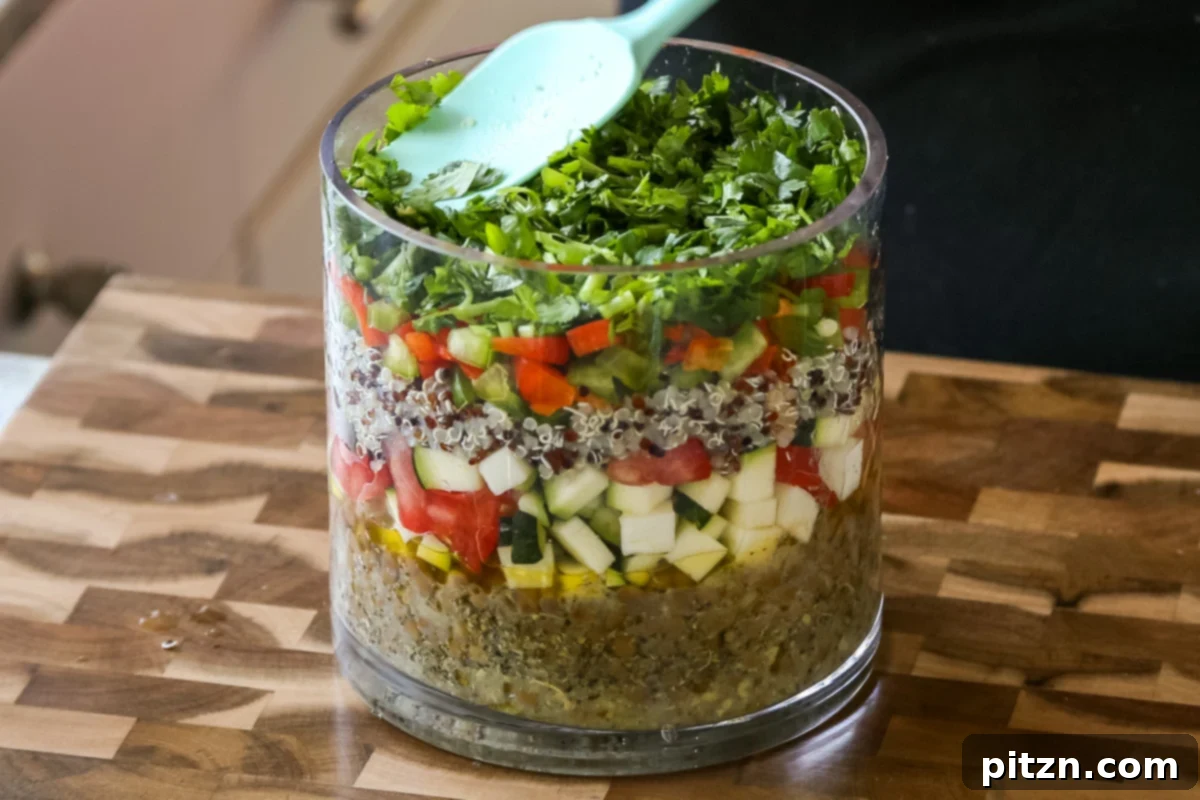 Effortless Lentil Quinoa Medley 18 A fresh layer of chopped cilantro being added to the salad, contributing its unique aroma and bright green color.