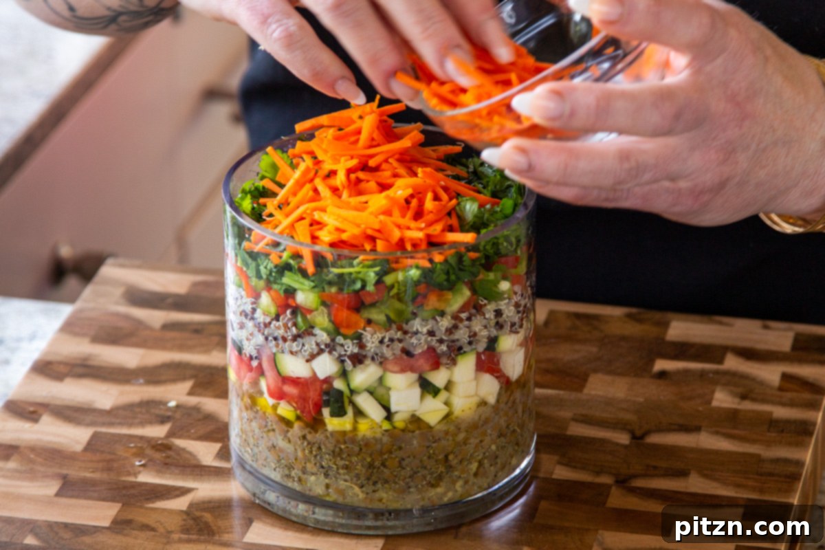 Effortless Lentil Quinoa Medley 19 Shredded carrots being gently placed into the jar, adding a sweet and earthy component to the layered salad.