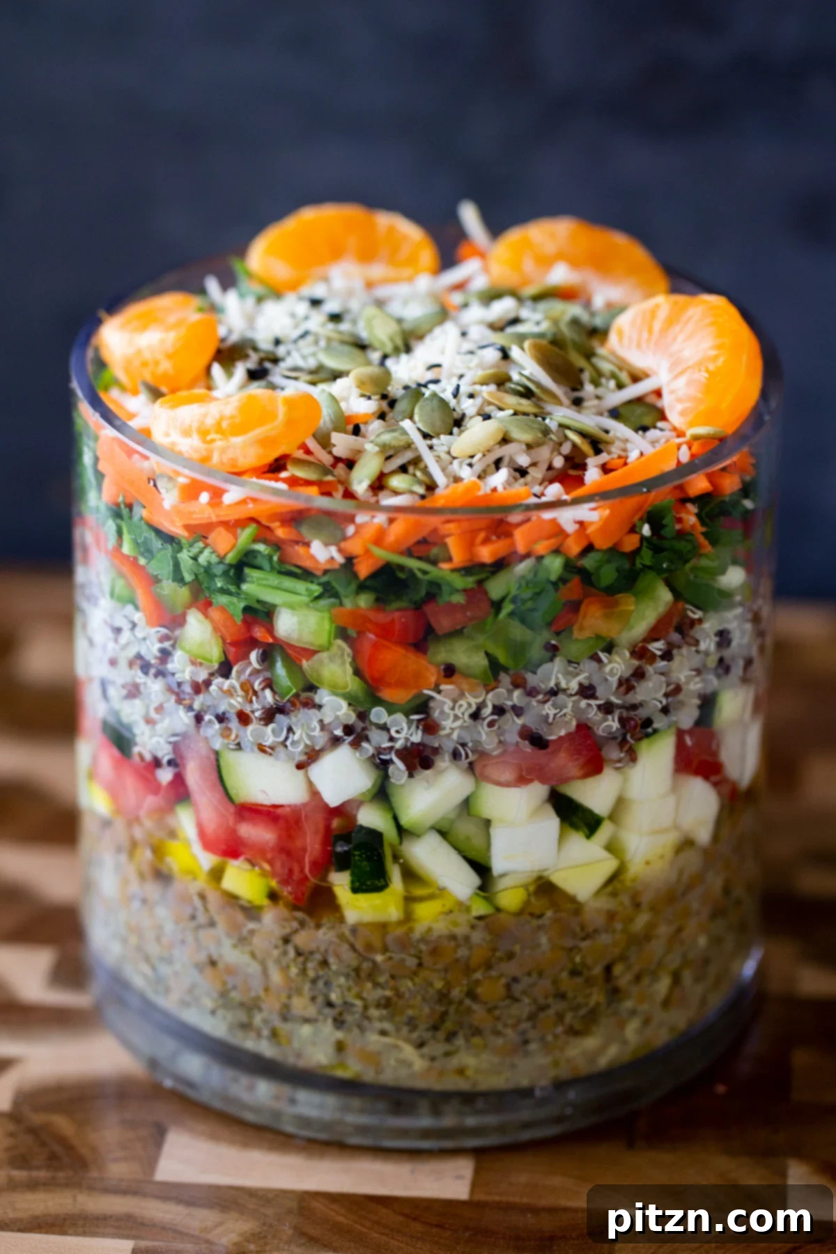 Effortless Lentil Quinoa Medley 3 Preparing a layered lentil quinoa salad, with fresh orange slices and seeds being added as a top layer for crunch and sweetness.