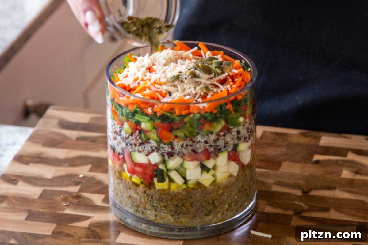 Effortless Lentil Quinoa Medley 20 A sprinkle of mixed seeds, including pumpkin and sesame, forming a crunchy layer at the top of the glass jar salad.