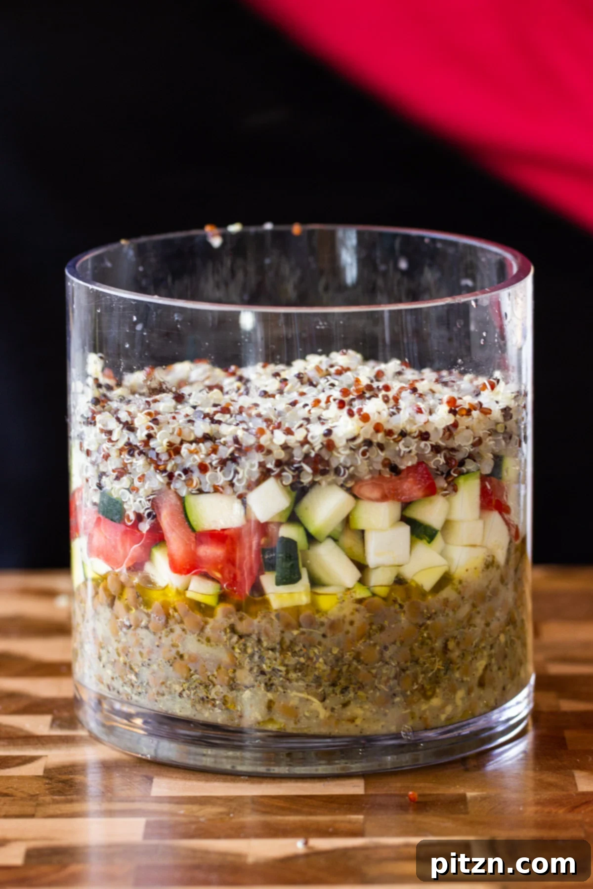 Effortless Lentil Quinoa Medley 6 The quinoa layer carefully placed into the glass jar as part of the make-ahead salad preparation.