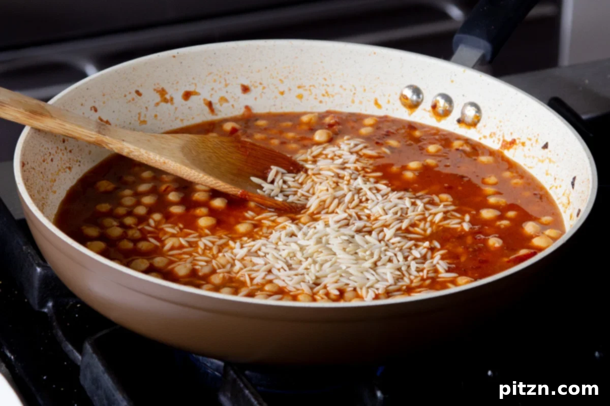 adding orzo and broth to the pan