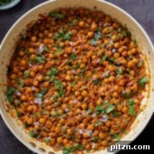 cajun orzo chickpeas in the pan after cooking with fresh herbs and onion on top