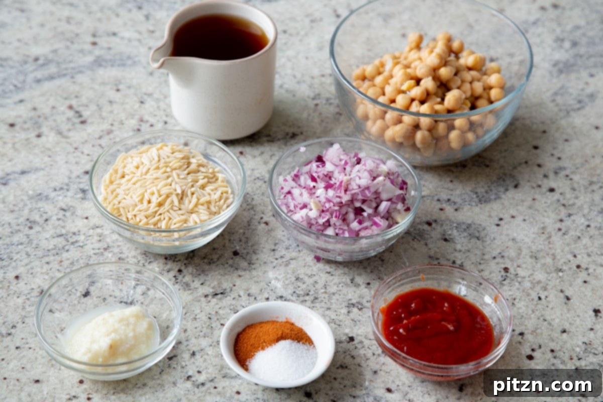 orzo, chickpeas, cajun spices, tomato paste, and garlic in cups on a kitchen counter