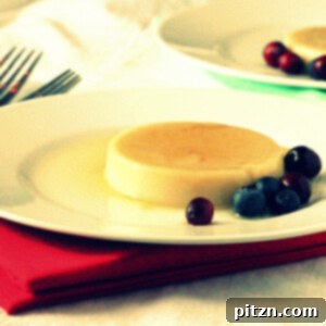 A caramel custard pudding on a white plate served with blueberries