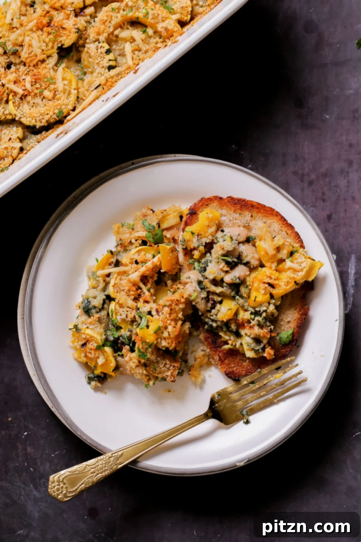 Comforting Delicata Squash and White Bean Casserole 2 delicata squash casserole on a plate next to the casserole dish