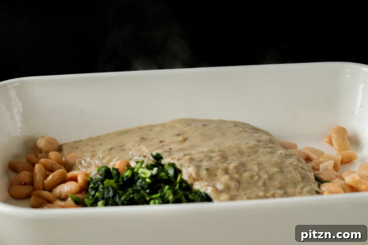 Comforting Delicata Squash and White Bean Casserole 17 adding white sauce to the spinach and white beans in the casserole dish