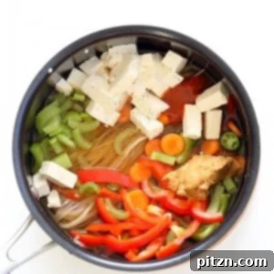 A vibrant bowl of one-pot peanut sauce noodles, garnished with fresh herbs and vegetables.