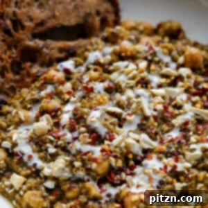 A bowl of rich chickpea, lentil, and quinoa spinach stew, perfectly seasoned and served with crusty bread for dipping.
