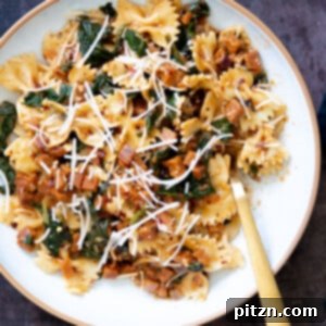 A vibrant bowl of vegan pepperoni pasta, showcasing homemade pepperoni, fresh spinach, and rich sauce.