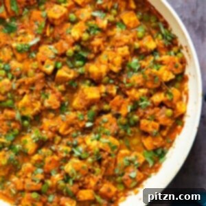 A rich Matar Tofu (tofu and pea curry) with a vibrant cumin tomato sauce, garnished with fresh herbs.