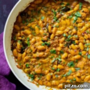 A pan of vibrant Kerala-style spicy white bean stew, garnished with fresh cilantro.