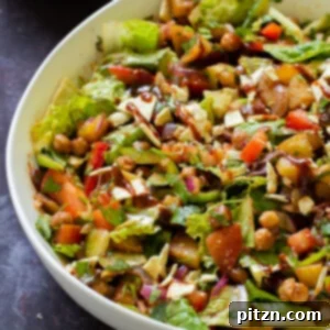 A close-up of a serving bowl filled with vibrant BBQ chickpea and potato salad, ready for a summer gathering.