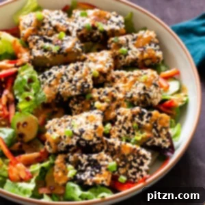A vibrant and appetizing crispy sesame tofu bowl, generously drizzled with rich peanut sauce.
