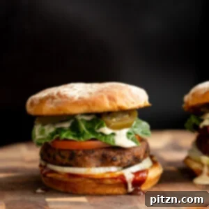 A savory side view of a vegan Cajun-spiced black bean quinoa burger, generously topped with creamy vegan ranch and spicy jalapeños.
