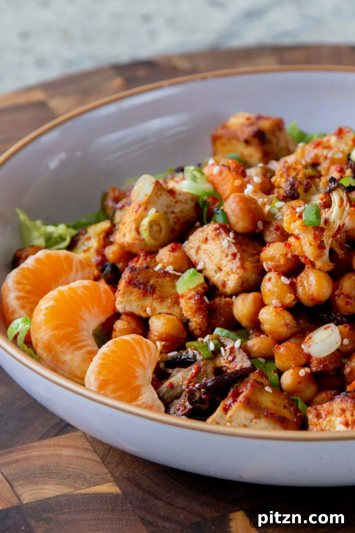Gochujang tofu and roasted vegetables artfully arranged in a bowl over fresh lettuce.