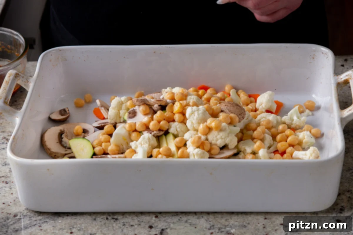 Adding cooked chickpeas to a bowl of chopped vegetables and tofu.